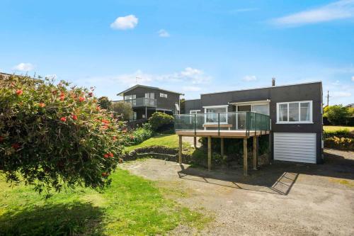 a house with a balcony in front of it at The Green Trout - Paraparaumu Beach Holiday Home in Paraparaumu Beach