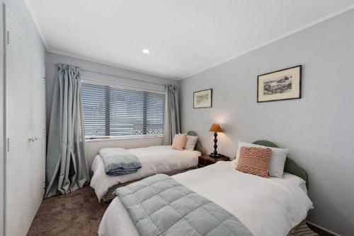 a bedroom with two beds and a window at Bach Relax - Mt Maunganui Holiday Home in Mount Maunganui