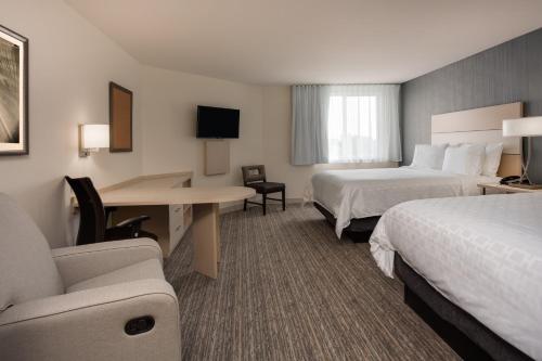a hotel room with two beds and a desk at Candlewood Suites Miami Intl Airport - 36th St by IHG in Miami