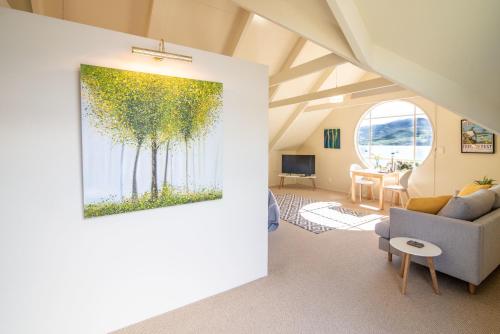 a living room with a painting of trees on the wall at The Boathouse - Akaroa Holiday Home in Akaroa