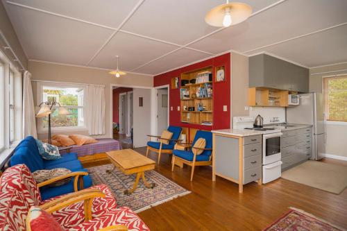 a living room with a blue couch and a kitchen at Mohuaiti - Golden Bay Holiday Home in Pakawau