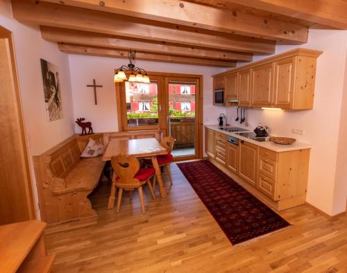 una cocina con armarios de madera, mesa y sillas en Appart Tramontana en Bürserberg
