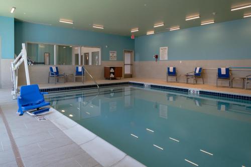 a swimming pool with a blue chair in a room at Holiday Inn Express & Suites - Tulsa Downtown - Arts District by IHG in Tulsa