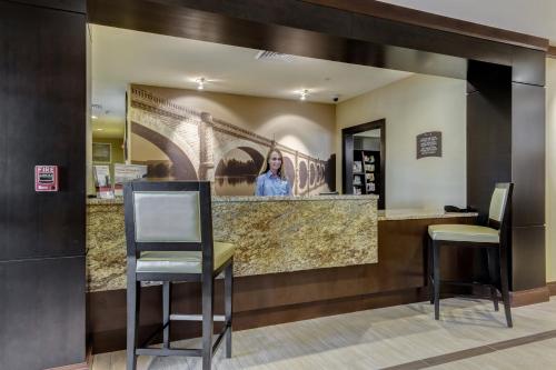 a bar in a hotel lobby with two chairs at Staybridge Suites St Louis - Westport by IHG in Maryland Heights