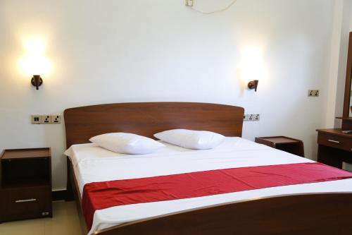 a bedroom with a bed with white sheets and a red blanket at Ananthi HOTELS in Vavuniya