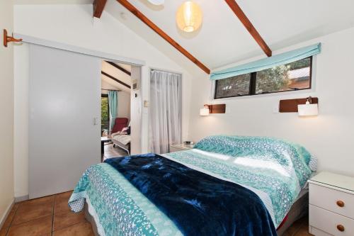 a bedroom with a bed with a blue comforter at The Cowshed Wairoro Park - Russell Holiday Home in Russell