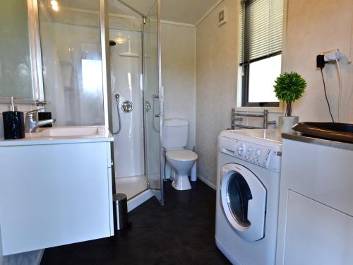 a bathroom with a washing machine and a toilet at Hector's Tiny House - Akaroa Holiday Home in Akaroa