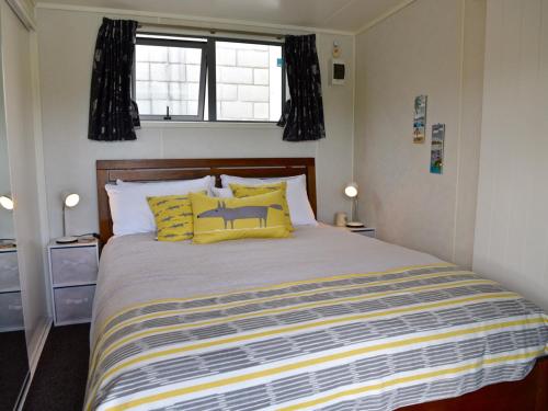 Hector's Tiny House - Akaroa Holiday Home في أكارو: غرفة نوم بسرير كبير مع مخدات صفراء