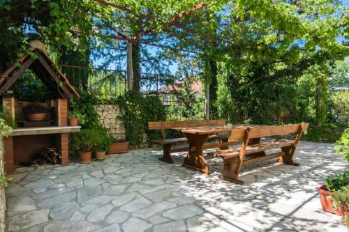 stół piknikowy i ławka w ogrodzie w obiekcie Apartments & Rooms Jokovic w mieście Mlini