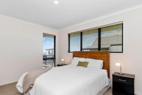 a white bedroom with a large bed and a window at Sparkling Ocean Views - Papamoa Holiday House in Papamoa