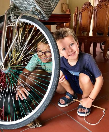 two young boys sitting next to a bike tire at Cato Homestay in Can Tho