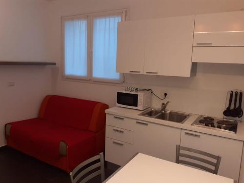 a small kitchen with a red chair and a microwave at Residence Villa Gori in Rimini