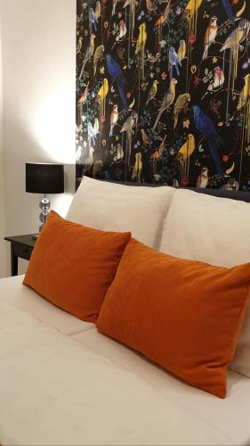 an orange pillow on a bed with a painting on the wall at Grand Paradise Apartman in Miskolc