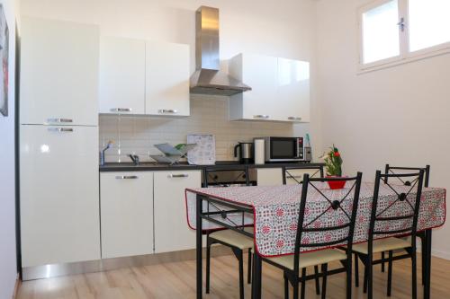 a kitchen with a table and chairs and a kitchen with white cabinets at Appart Aux deux Colombes avec Balcon et Garage in Pamiers