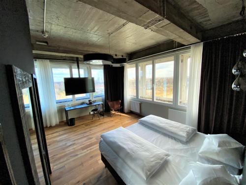 a bedroom with a bed and a tv and windows at LOFTSTYLE Hotel Hannover, Best Western Signature Collection in Hannover