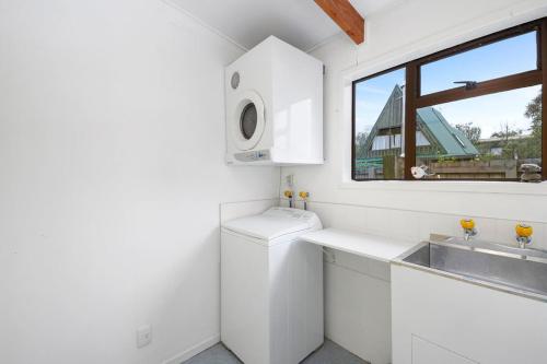 KuratauにあるParehopu Lake House - Taupo Holiday Homeのシンクと窓のある白いキッチン