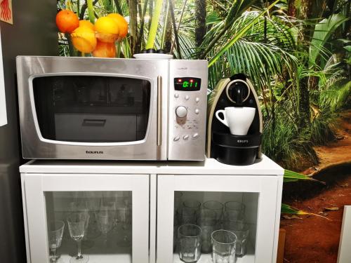 un four micro-ondes installé au-dessus d'une armoire blanche avec des verres dans l'établissement Salou luz y color, à Salou