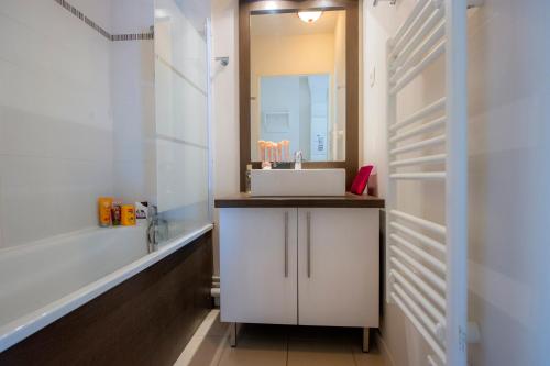 a bathroom with a sink and a mirror and a tub at Goélia Résidence Du Parc in Gonneville-sur-Honfleur