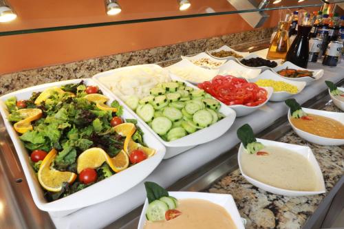 a buffet with several trays of vegetables and other foods at Staybridge Suites Guadalajara Expo by IHG in Guadalajara
