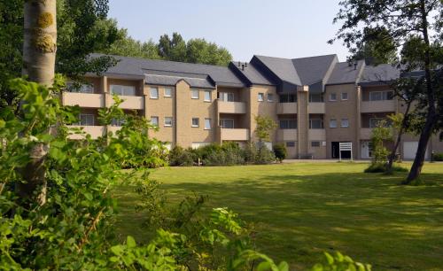 an apartment building with a lawn in front of it at Domein Westhoek Apartment in Oostduinkerke