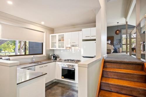 a kitchen with white cabinets and a staircase at The Edge Villa in Mount View