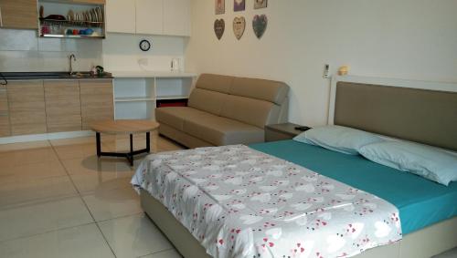 a bedroom with a bed and a couch and a table at hasanah evo studio suites in Kampong Sungai Ramal Dalam