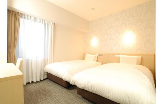 two beds in a hotel room with a window at AB Hotel Fuji in Fuji