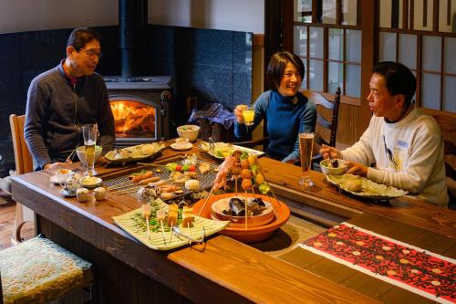 un grupo de personas sentadas alrededor de una mesa con comida en Sanchouka, en Saga