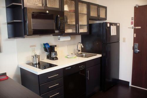 a kitchen with black cabinets and a black refrigerator at Candlewood Suites Youngstown W - I-80 Niles Area by IHG in Austintown