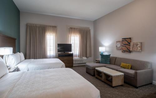 a hotel room with two beds and a couch at Staybridge Suites Houston East - Baytown by IHG in Baytown