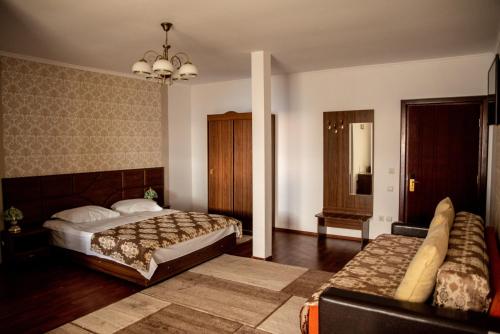 a bedroom with two beds and a couch at Pensiunea Eden in Ranca