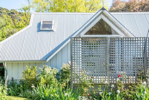 a house with a picket fence around a garden at The Boathouse - Akaroa Holiday Home in Akaroa