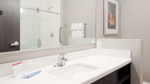 a white bathroom with a sink and a mirror at Candlewood Suites Grand Island by IHG in Grand Island