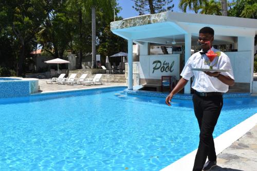 a man in a uniform standing next to a swimming pool at Tropical Casa Laguna in Cabarete