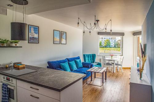 uma cozinha e uma sala de estar com um sofá azul em Apartament Zatoka em Puck