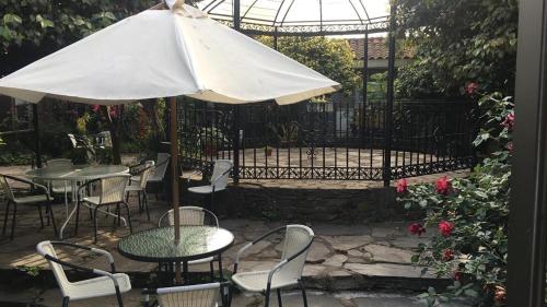 a patio with tables and chairs and an umbrella at Casona Patrimonial Cobquecura Hotel Boutique in Cobquecura