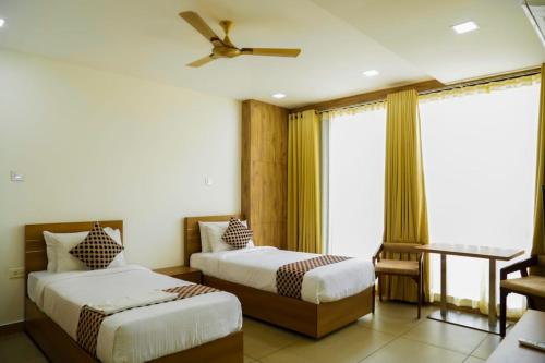1 dormitorio con 2 camas y ventilador de techo en KB RESIDENCY, en Kozhikode