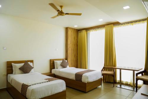 a bedroom with two beds and a ceiling fan at KB RESIDENCY in Kozhikode