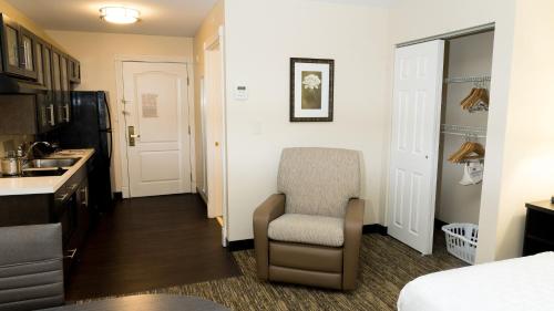 a room with a chair and a kitchen with a sink at Candlewood Suites Saint Joseph - Benton Harbor by IHG in Stevensville