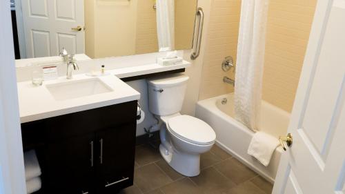 a bathroom with a toilet and a sink and a tub at Candlewood Suites Saint Joseph - Benton Harbor by IHG in Stevensville