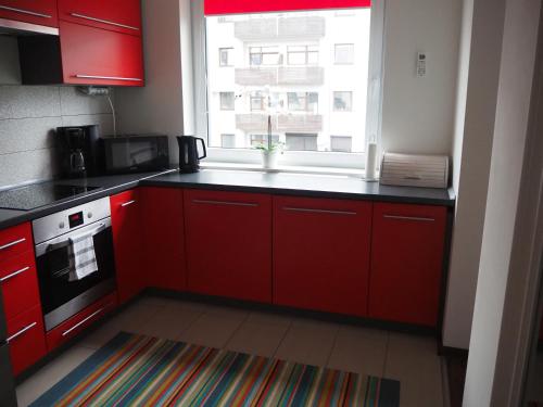 kuchnia z czerwonymi szafkami i oknem w obiekcie Szybowników 2 w mieście Piła