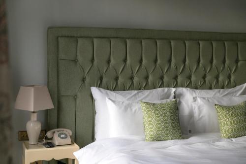 a bed with a green headboard and a phone on a table at Vazisubani Estate in Vazisubani