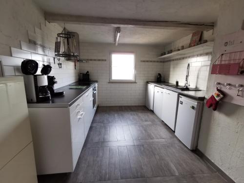 a large kitchen with white cabinets and a window at Ferienwohnung Dölzig in Schkeuditz