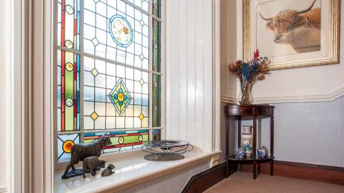 a stained glass window with two figurines on a shelf at Kiltearn Guest House in Evanton