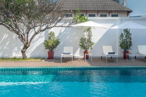 a pool with chairs and umbrellas next to a building at Le Charme Vientiane Hotel in Vientiane