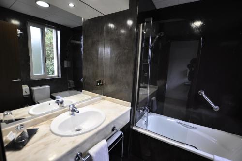 a bathroom with two sinks and a shower and a tub at Hotel Rio Bidasoa in Hondarribia