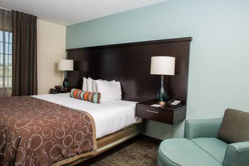une chambre d'hôtel avec un lit et une chaise dans l'établissement Staybridge Suites Lincoln North East, an IHG Hotel, à Lincoln