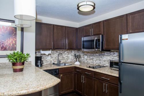 a kitchen with wooden cabinets and a stainless steel refrigerator at Staybridge Suites Lincoln North East, an IHG Hotel in Lincoln