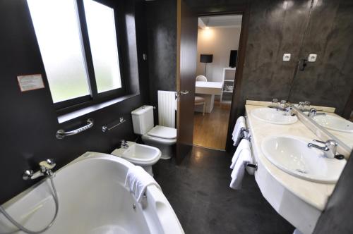 a bathroom with two sinks and a tub and a toilet at Hotel Rio Bidasoa in Hondarribia