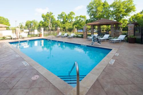 einen Pool mit Stühlen und einem Pavillon in der Unterkunft Staybridge Suites - Lake Jackson, an IHG Hotel in Lake Jackson